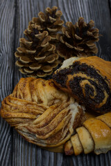 Cinnamon and poppy seed buns. Rich pastries. Nearby pine cones. Close-up shot.