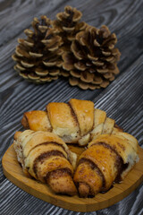Cinnamon croissants. Rich pastries. Nearby pine cones. Close-up shot.