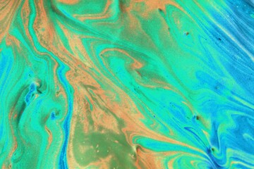 Blue-yellow-green abstract marble background. The acrylic paint mixes freely and creates an...