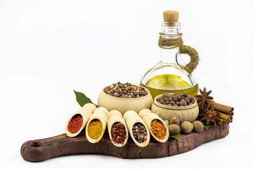 Olive oil, spices, in wooden tableware lie on a kitchen board it is isolated on a white background.