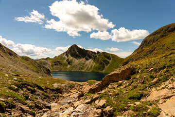 Fanealm und Wilder See in Suedtirol, Italy, Alpine pastures with a deep blue lake, green meadows and a blue sky with fleecy clouds, in summer