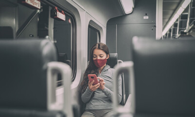 Train passenger using mobile phone during travel commute wearing face mask for coronavirus...