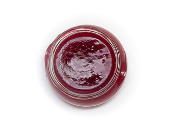 Red currant jam in a glass jar on a white background top view