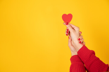 Valentine's day background. Female hands holding red peper heart on yellow background. Health care...
