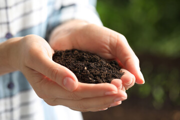 Woman with handful of soil outdoors, closeup