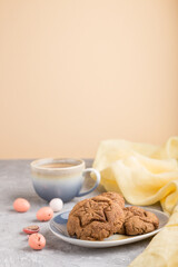 homemade oatmeal cookies with a cup of cocoa on a gray and orange background. side view, selective focus.