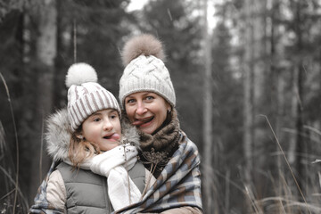 Fototapeta premium Mom and daughter. Portrait on the background of the autumn forest. Fashion winter clothes. Happy motherhood and childhood