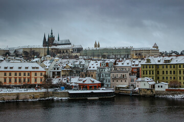Naklejka premium Postcard view of Prague Castle from Charles Bridge, Czech republic.Famous tourist destination.Prague winter panorama.Snowy day in the city.Amazing European cityscape cold weather.Romantic atmosphere.