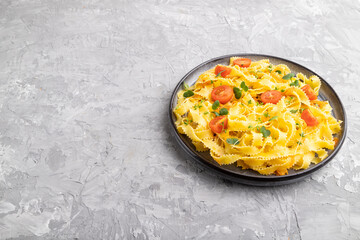 Reginelle pasta with tomato, eggs and microgreen sprouts on a gray concrete background. Side view, copy space.