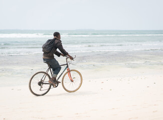 Fototapeta premium African young man riding bike on tropical beach