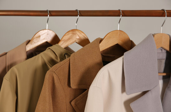 Different warm coats on rack against light grey background, closeup