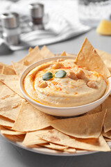 Delicious creamy hummus served with chips on table, closeup