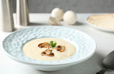 Delicious cream soup with mushrooms on white table