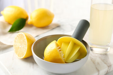 Plastic citrus squeezer with lemon half in bowl on table