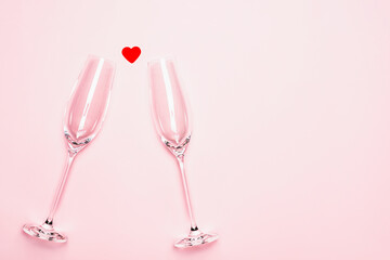 Champagne glasses and a red heart on a pink background. Valentine's day, wedding, romance concept.