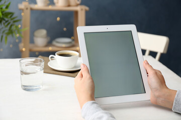 Young woman using new modern tablet in kitchen, closeup