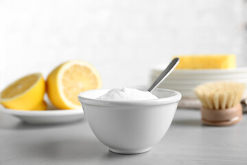 Bowl of baking soda, brush and lemon on light grey table