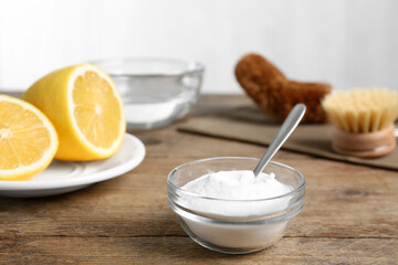 Baking soda in glass bowl on wooden table. Natural detergent
