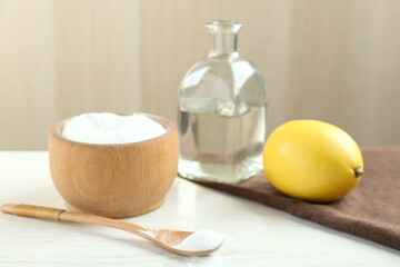 Fototapeta na wymiar Baking soda, cut lemon and vinegar on white wooden table