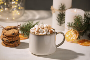 Cup of hot drink with marshmallows and cookies on white table