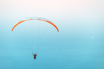 Group of paragliders flying in the blue sky. Extreme and air activity and sport concept. Blue sea at the background