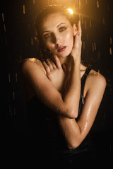 portrait of a Beautiful girl in a black dress under trickles of water, aqua studio, drops flow down...