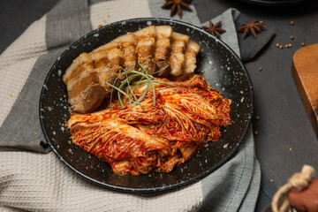 Korean Boiled Pork with preparing cabbage kimchi in black dish. Korean traditional cuisine. Fermented food.