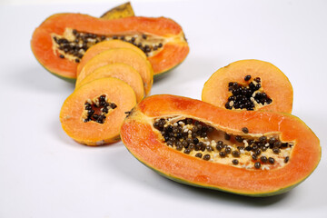 Whole Papaya fruit with a few slices isolated on a bright background. Close-up of juicy and delicious fresh papaya. Overripe papaya that starts to rot will give off a sweet, honey-like liquid.