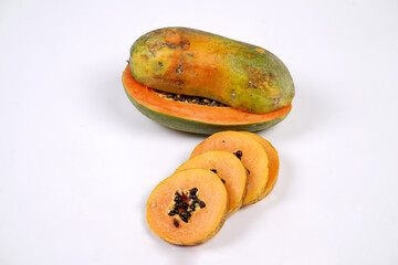 Whole Papaya fruit with a few slices isolated on a bright background. Close-up of juicy and delicious fresh papaya. Overripe papaya that starts to rot will give off a sweet, honey-like liquid.