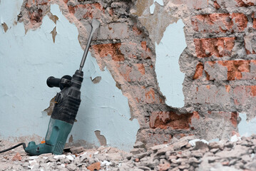 Hammer drill with chisel on the old brick wall background. Removing an old putty from the wall...