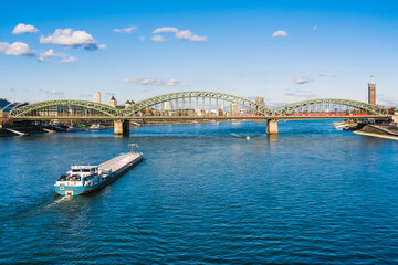 Cologne Koln K&ouml;ln, Germany, Panorama view of the Rhine River with Hohenzollernbr&uuml;cke, Cargo Ship and Blue Sky
