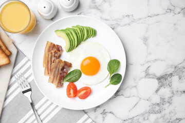 Tasty breakfast with fried egg, bacon and avocado served on white marble table, flat lay