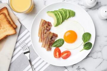 Tasty breakfast with fried egg, bacon and avocado served on white marble table, flat lay