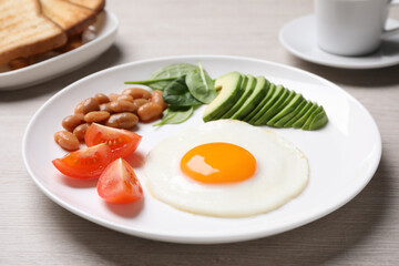 Tasty breakfast with fried egg, beans and avocado served on white wooden table, closeup