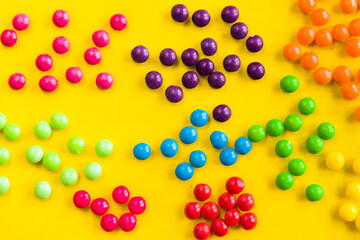 Skittles candy on the yellow table, colorful sweet candy background