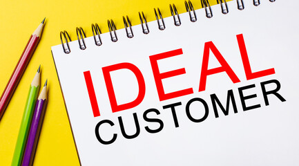 IDEAL CUSTOMER on a white notepad with pencils on a yellow background. Business concept