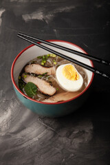 Composition with a bowl of rice noodles, meat and vegetables