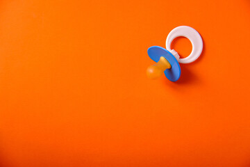 Baby blue pacifier on an orange background, place for an inscription