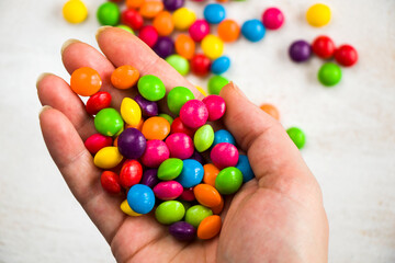Fototapeta na wymiar Skittles candy in hand, colorful sweet candy background