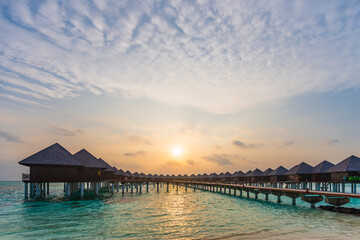 Fototapeta na wymiar The rising sun over Maldivian stilt houses.