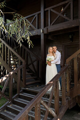 Beautiful bride and groom near a wooden stylish house. Sunny day.