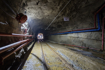 Naklejka premium Underground gold mine shaft tunnel drift with rails and light
