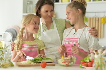 Portrait of cute girls with mother cooking in kitchen