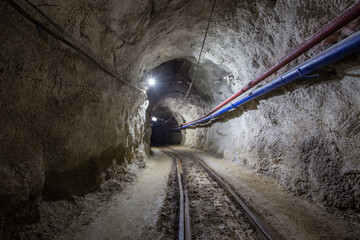 Underground gold mine shaft tunnel drift with rails and light