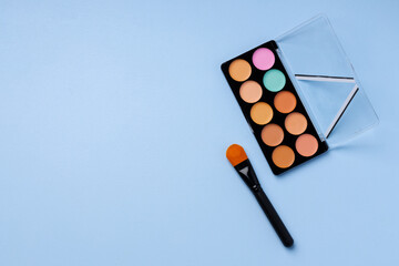 Complexion make up products and brush on blue background