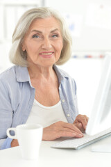 Portrait of senior woman working in office with computer