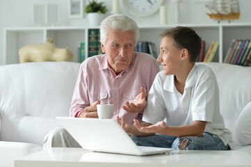 Obraz premium Boy and grandfather with a laptop at home