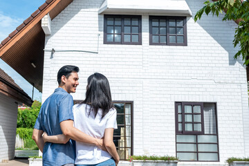 An Asian couple, husband and attractive wife, are happiness with new home where they are relocation background, to beginning of family life concept.