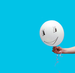 White balloon on a blue background. A funny face is drawn on the ball.