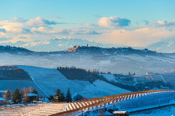 Italy Piedmont: Barolo wine yards unique landscape winter sunset, La Morra medieval village castle on hill top, the Alps snow capped mountains background, italian heritage grape agriculture
